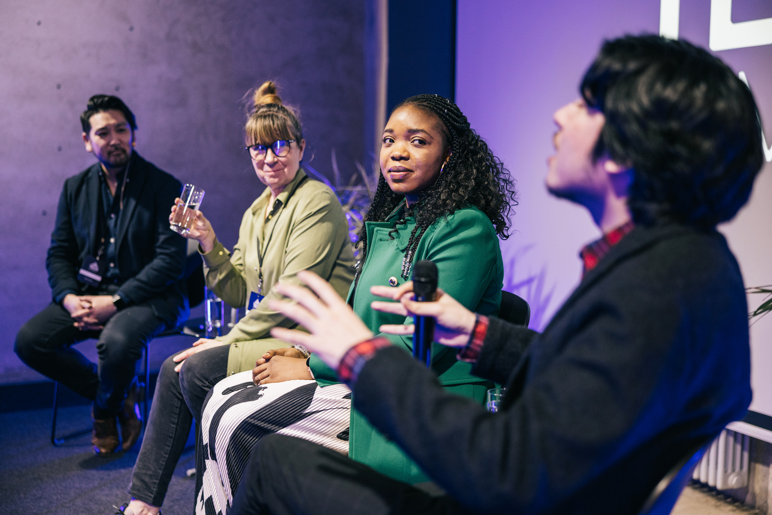 Diverse business people talking during panel discussion at tech conference.