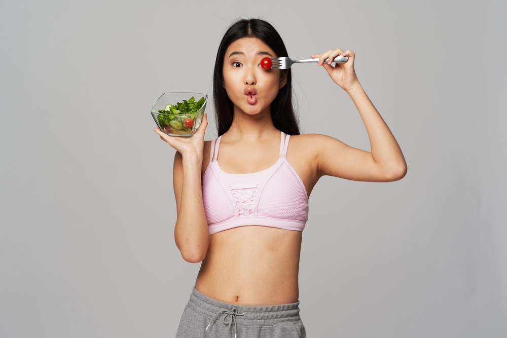  Woman Holding Salad and a Tomato Covering Her Eye